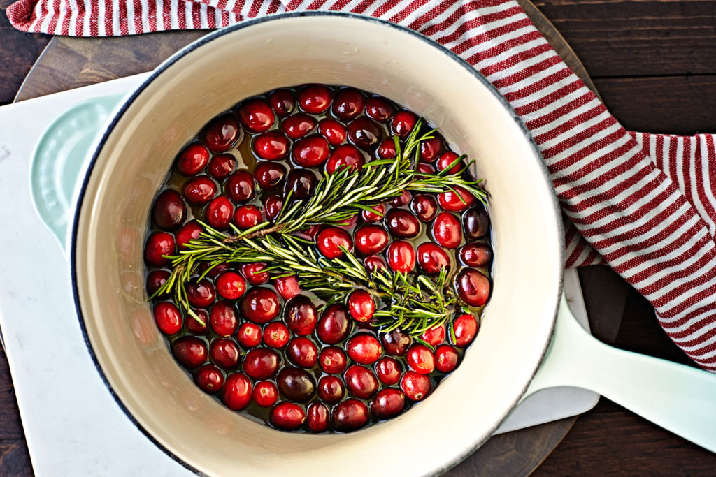 Cranberries and rosemary in a pan of sugar syrup