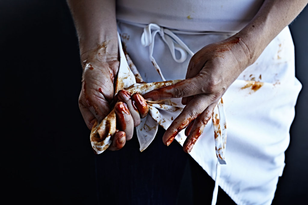 Woman wiping barbecue sauce covered hands on her apron.