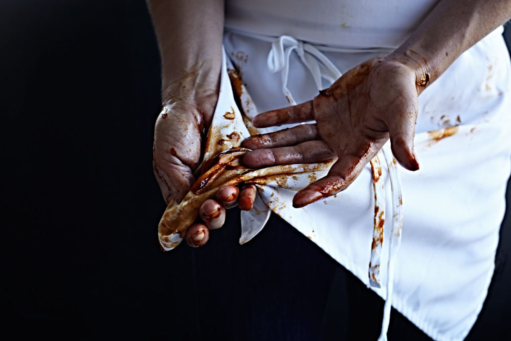 Woman wiping barbecue sauce covered hands on her apron.