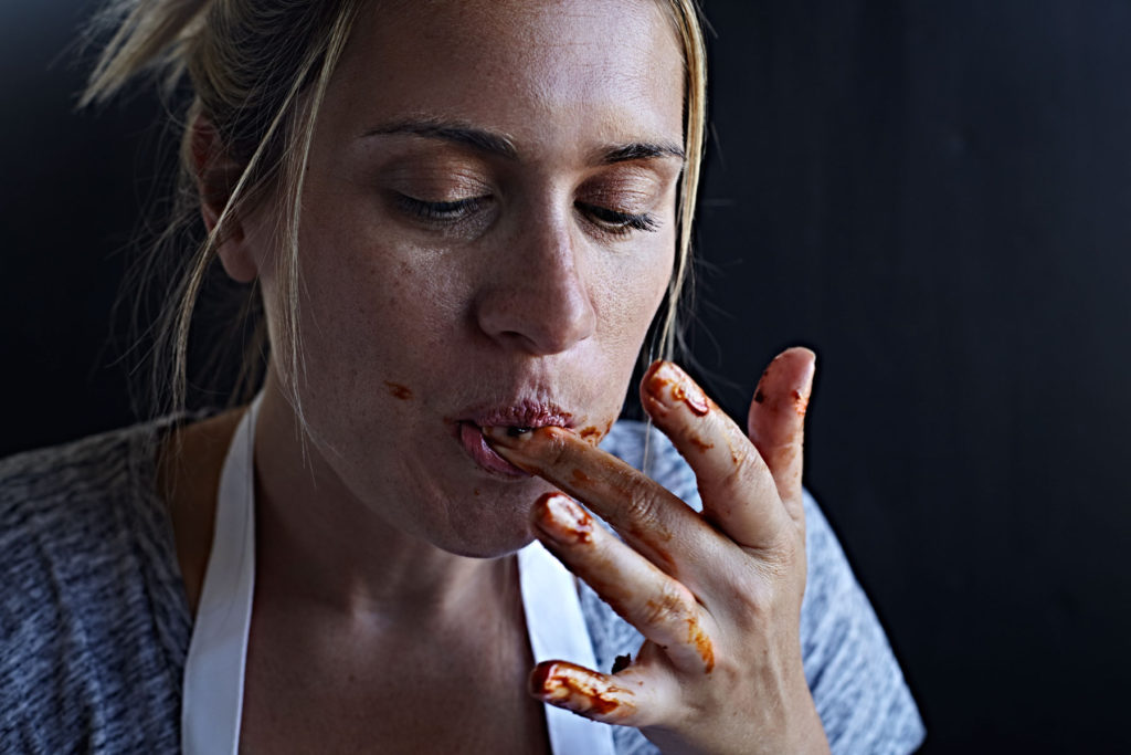 Woman licking barbecue sauce off of her fingers.