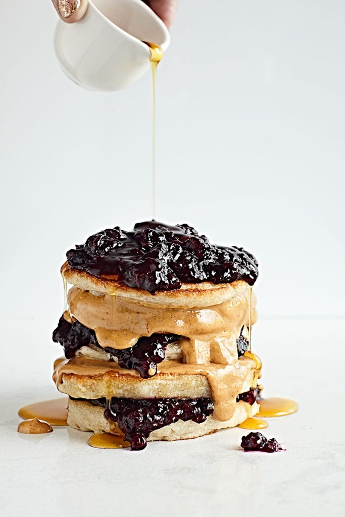 Sourdough pancakes stacked with peanut butter and blueberry jelly.