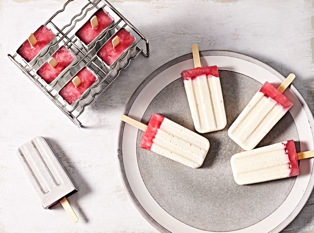 Creamy cheesecake rhubarb popsicles in a mold and on a plate.