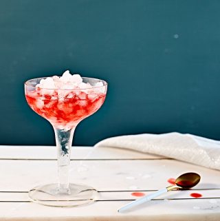 Dirty Shirley temple cocktail over crushed ice in vintage coupe glass.