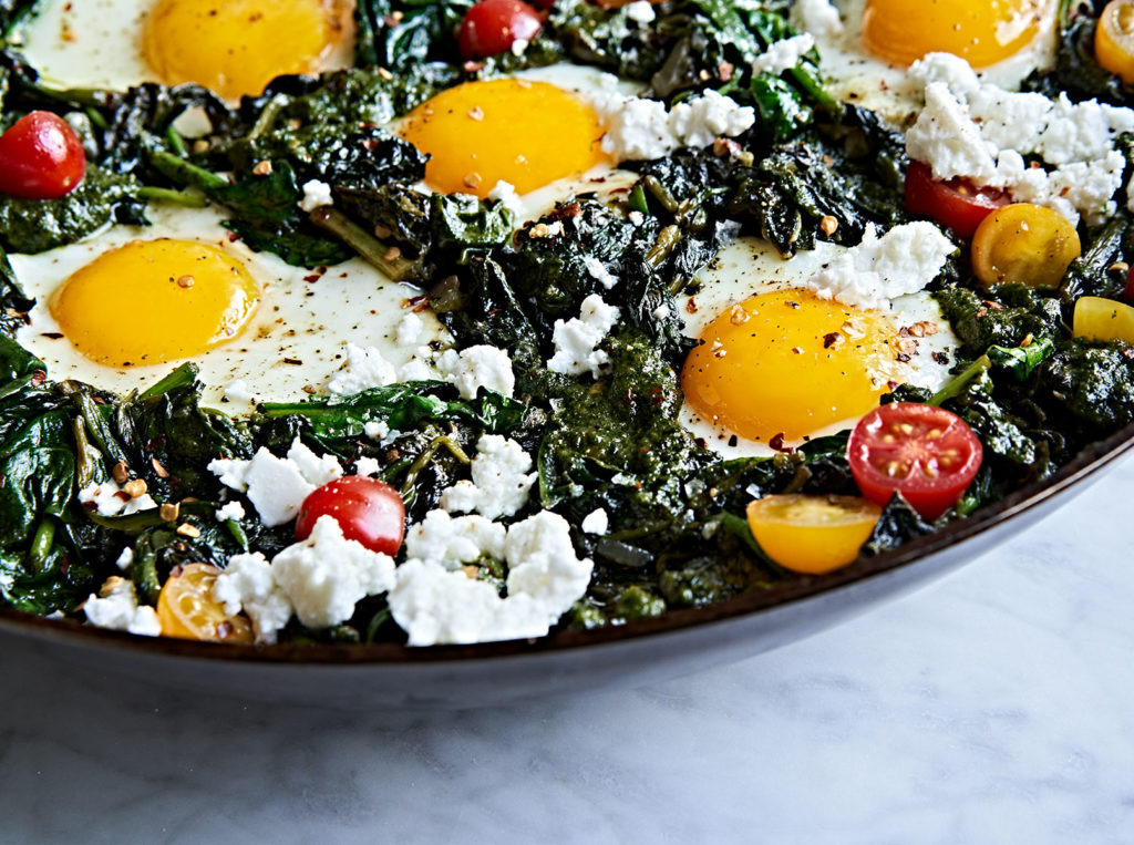 Green spinach and kale shakshuka with sunny-side up eggs and feta.