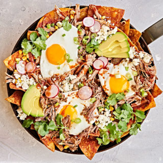 Chilaquiles breakfast with sunny-side egg in skillet.