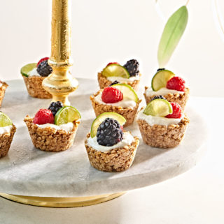 Bite-sized granola yogurt cups with berries and lime on two tiered stand.