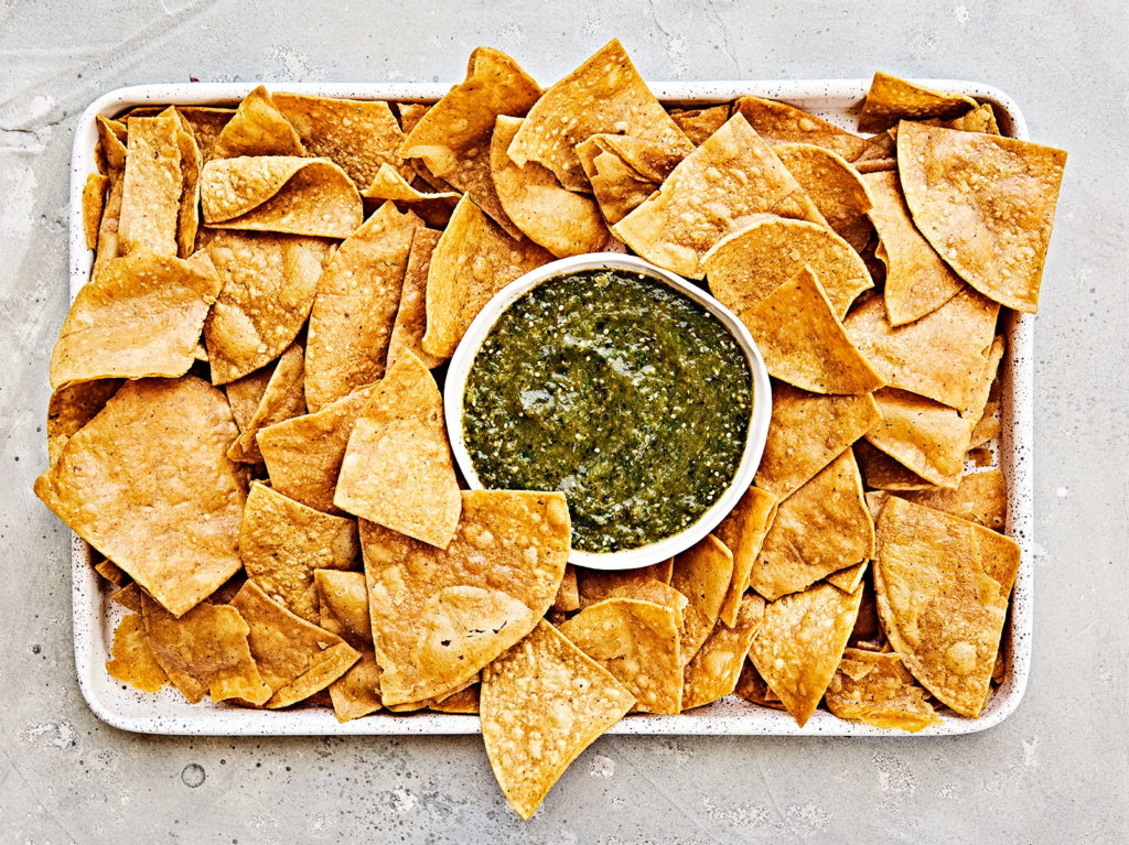 Fire roasted salsa verde surrounded by tortilla chips on a tray.
