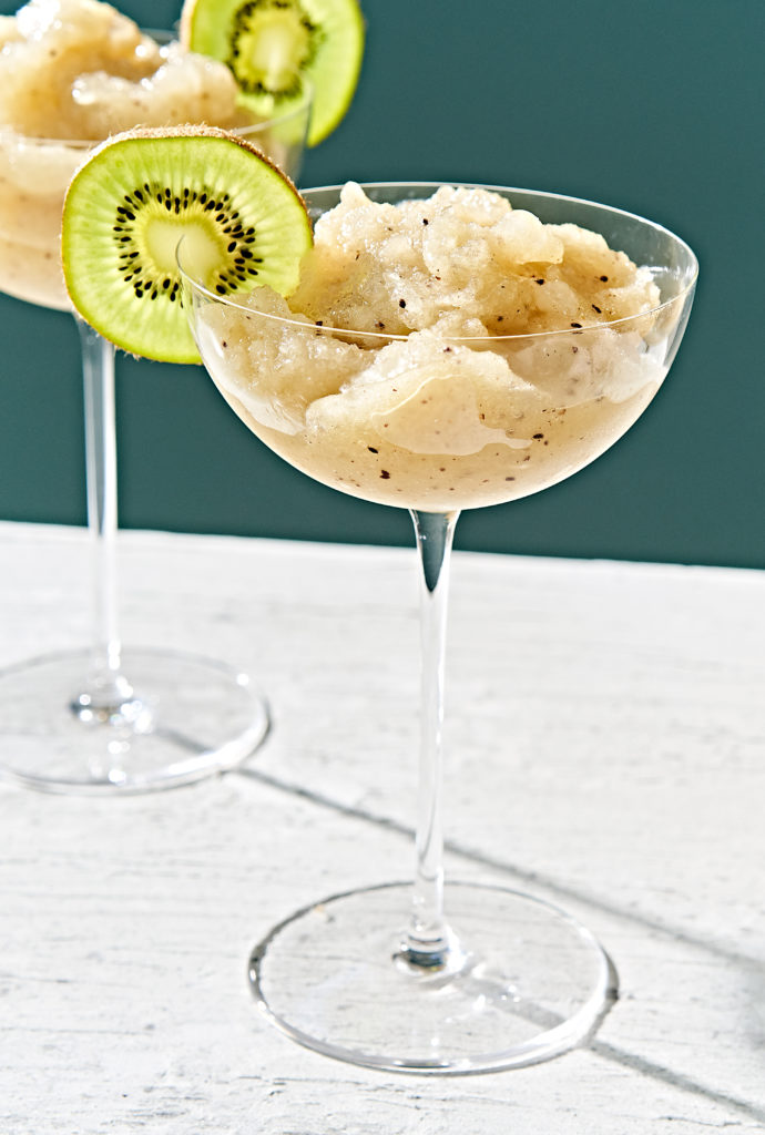 Kiwi slush margarita in stemmed glass garnished with kiwi slice.