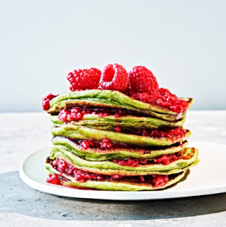 Stack of green monster pancakes made with spinach and topped with raspberries.